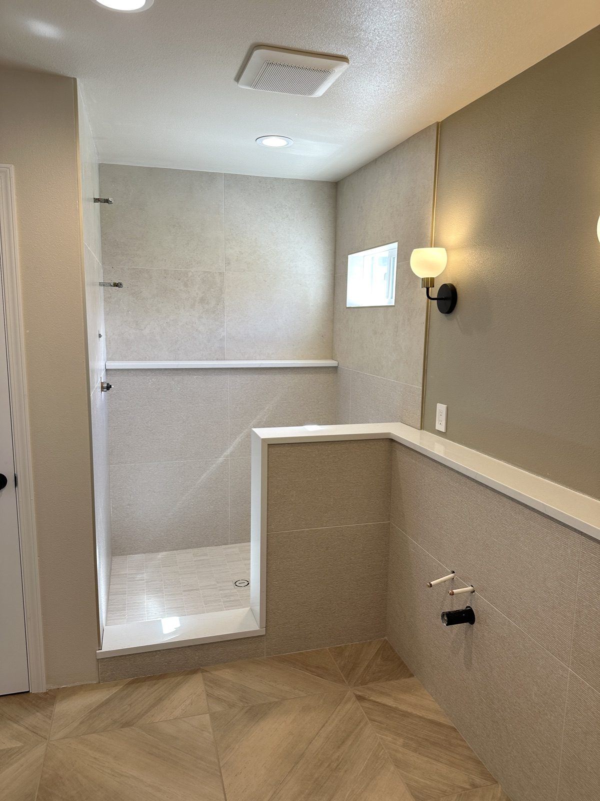 Walk-in shower with large-format porcelain walls, a full-width shelf, and a pony wall with a solid cap